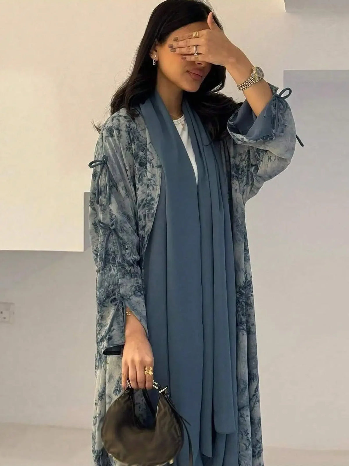 Eine Frau trägt eine fließende blau-tiegedruckte Abaya-Kaftan mit langen Ärmeln und einem passenden Schal.