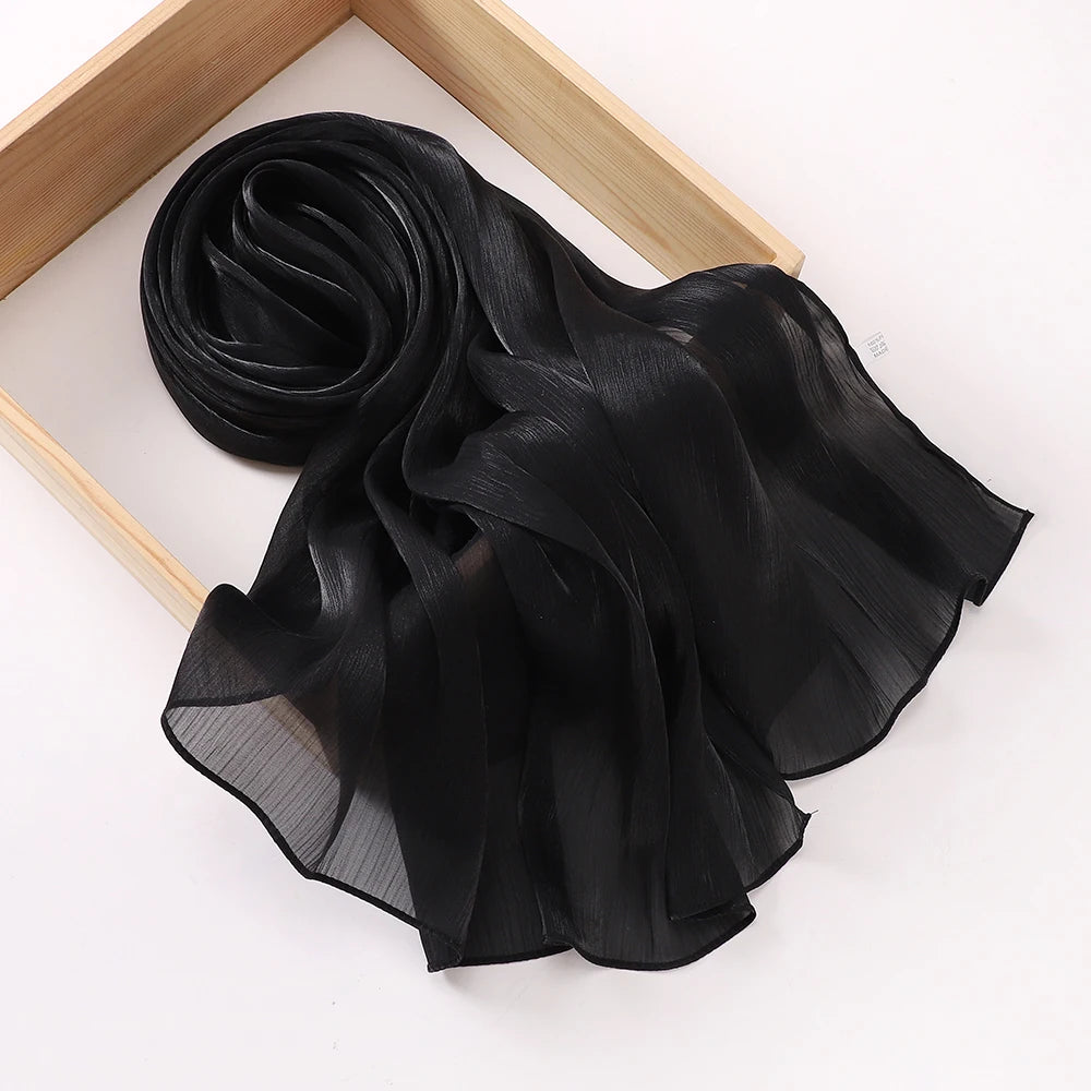 Châle hijab en mousseline crinklée noire drapé sur un cadre en bois.