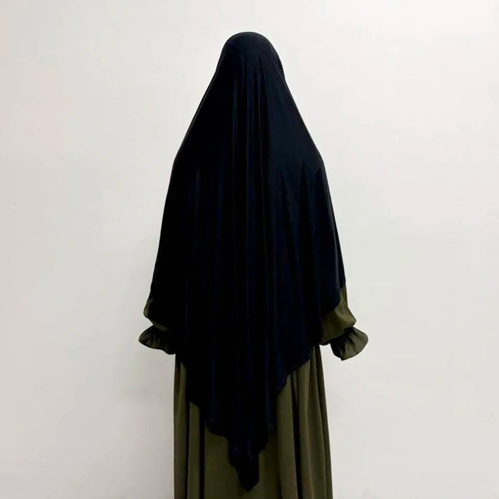 Eine Frau trägt einen schwarzen, atmungsaktiven Bambus-Jersey-Khimar-Hijab über ein grünes Kleidungsstück.