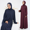 Una mujer vistiendo un vestido abaya suelto y fluído de color azul marino oscuro para la oración.