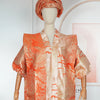A model wearing an orange satin kaftan abaya with textured patterns.