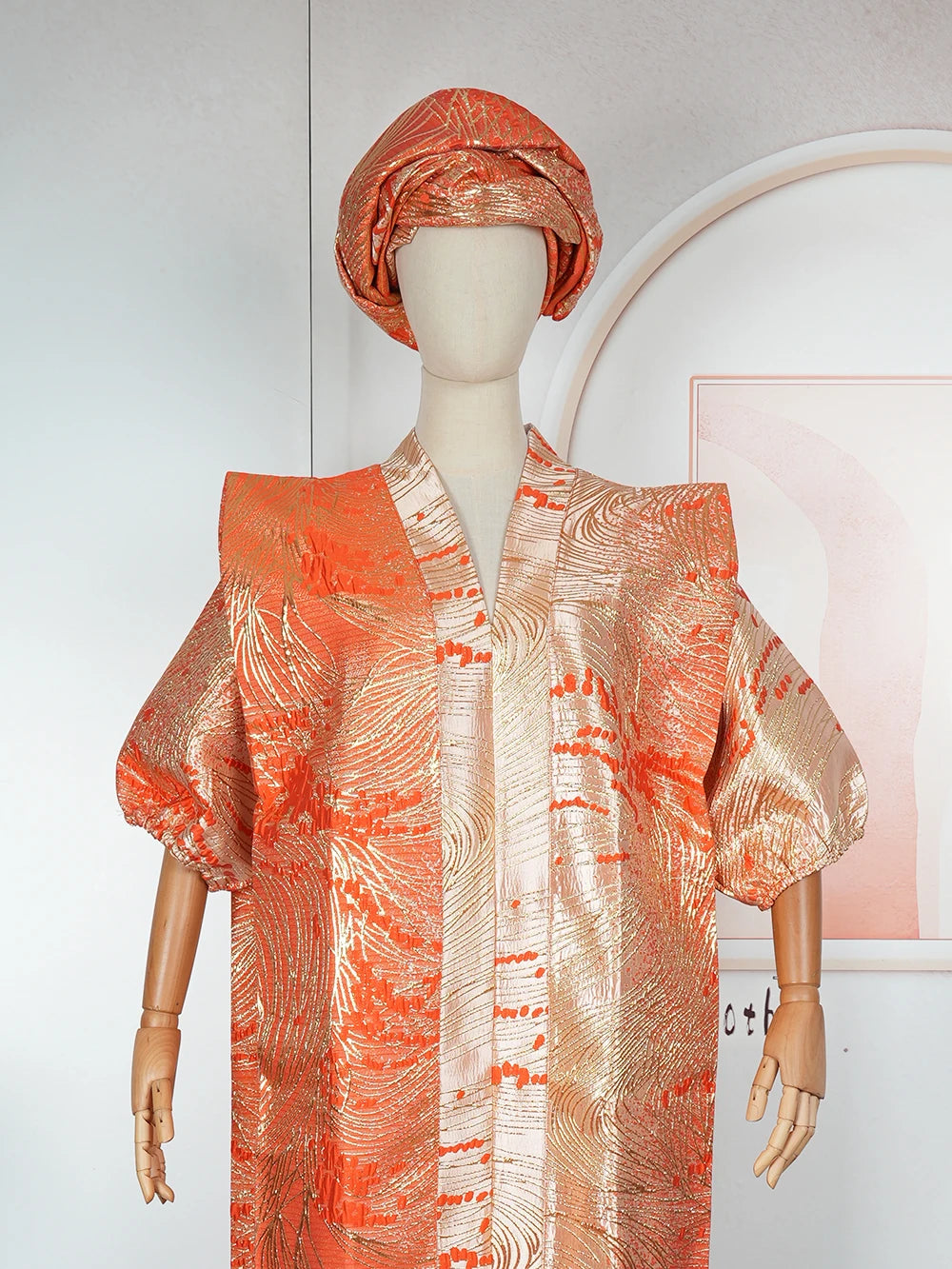 A model wearing an orange satin kaftan abaya with textured patterns.