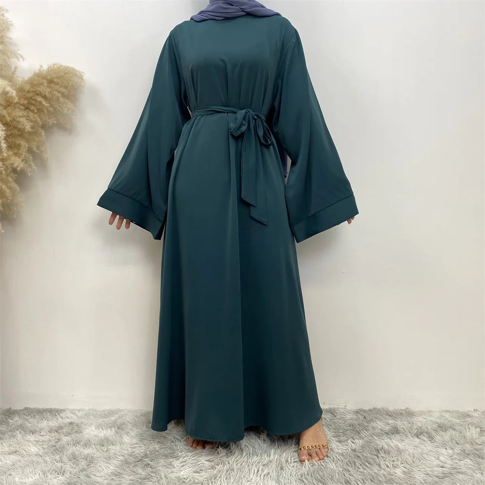 Una elegante abaya de encaje color verde azulado oscuro, de mangas largas y cintura atada.