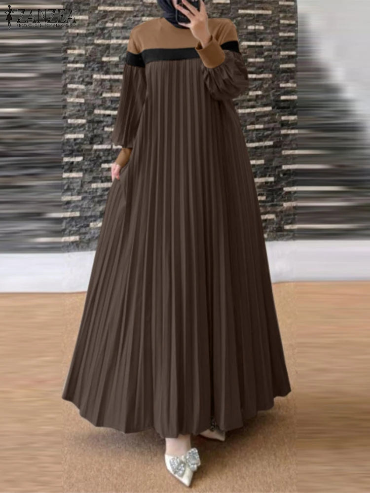 Une femme portant une longue caftan marron plissé à bordure noire et un hijab foncé.