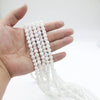 Una mano sostiene una cuenta de cuentas blancas usadas para la oración musulmana (tasbih) con borlas de luna y estrella.