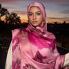 Eine Frau trägt einen rosa-lila schimmernden Seiderschal aus Satin über einem orangefarbenen Sonnenuntergang.