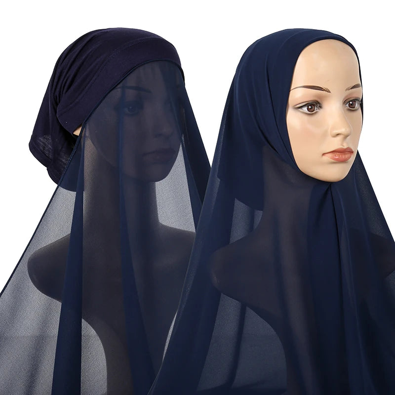 A model wearing a navy blue chiffon instant hijab with a sheer overlay and modal cotton cap.