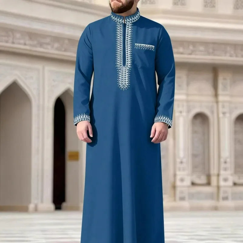 Un hombre vistiendo una juba thobe casual de azul marino bordada con cuello alto y costura plateada.