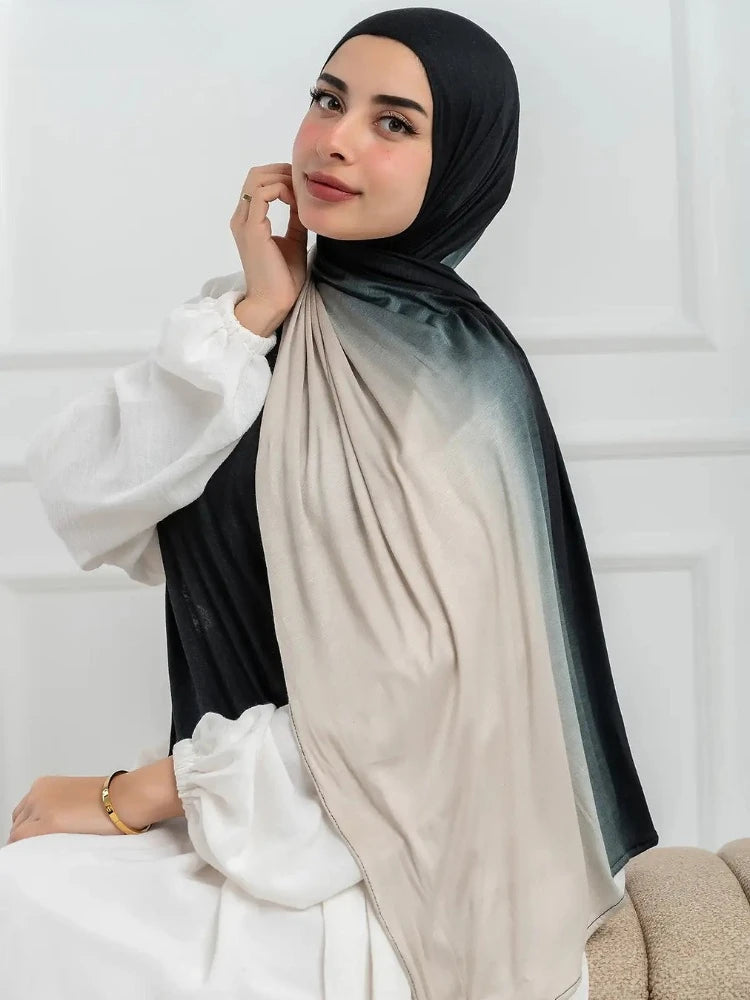 Una mujer vistiendo un pañuelo hijab de algodón gradiente doble cara en tonos negro y beige.