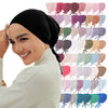 Eine Frau präsentiert einen schwarzen Inner-Hijab-Bonnet und einen cremefarbenen Rollkragenpullover neben einer Display mit m