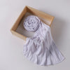 A white ribbed jersey hijab scarf is rolled and draped within a light wooden frame.