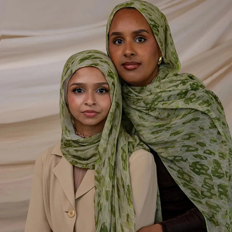Une femme portant un hijab à motifs vert clair et un blazer beige.