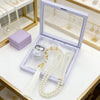 A light purple box containing pearl tasbih prayer beads and a digital counter bracelet displayed on a white surface.