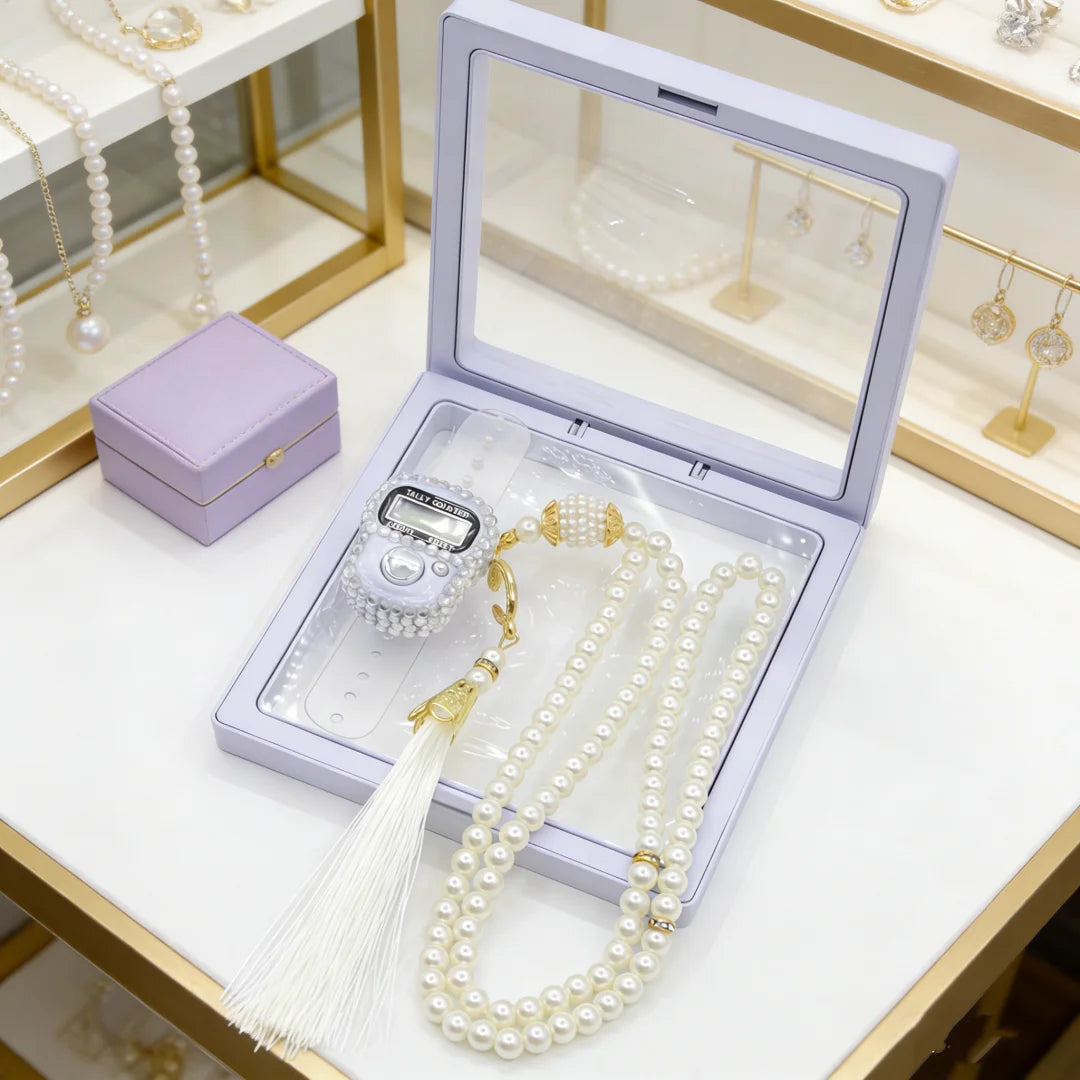 A light purple box containing pearl tasbih prayer beads and a digital counter bracelet displayed on a white surface.