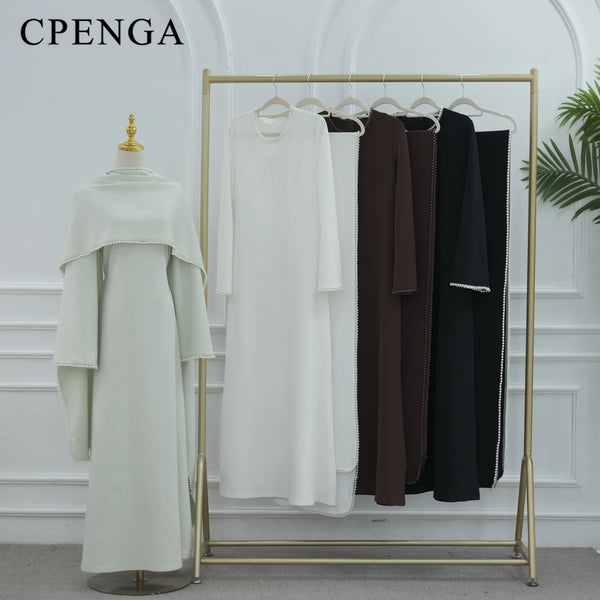 A display rack showing several elegant modest abaya dresses in various colors and styles.