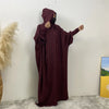 Une abaya marron avec capuche et manches batwing, exposée contre un mur blanc.