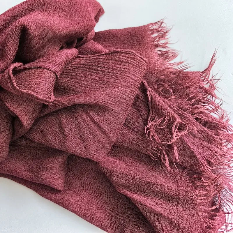 Gros plan d'un foulard hijab en viscose de couleur rose poussiéreux avec franges et pompon.