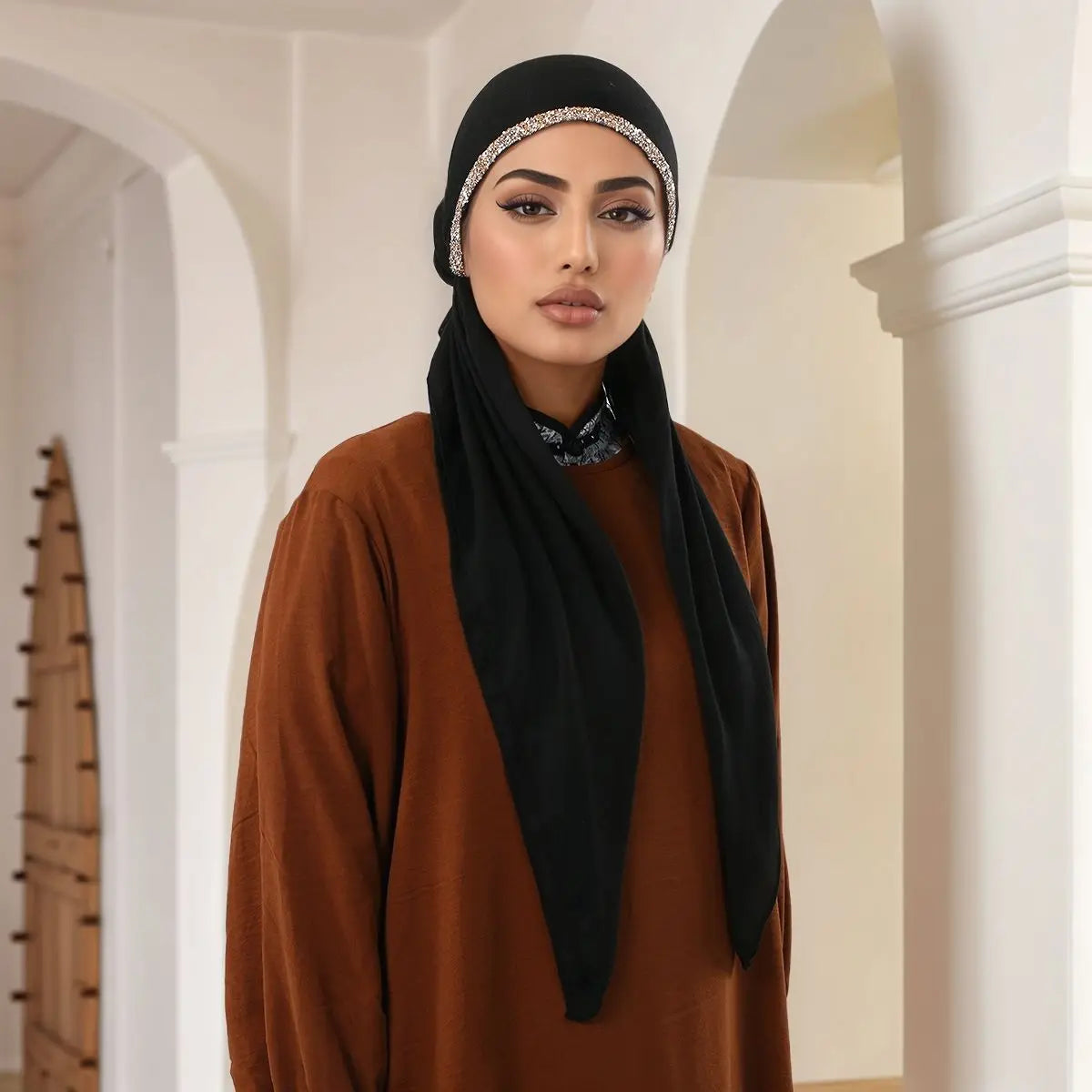 Une femme portant un foulard modal noir avec des incrustations de diamants et un bandeau doré.