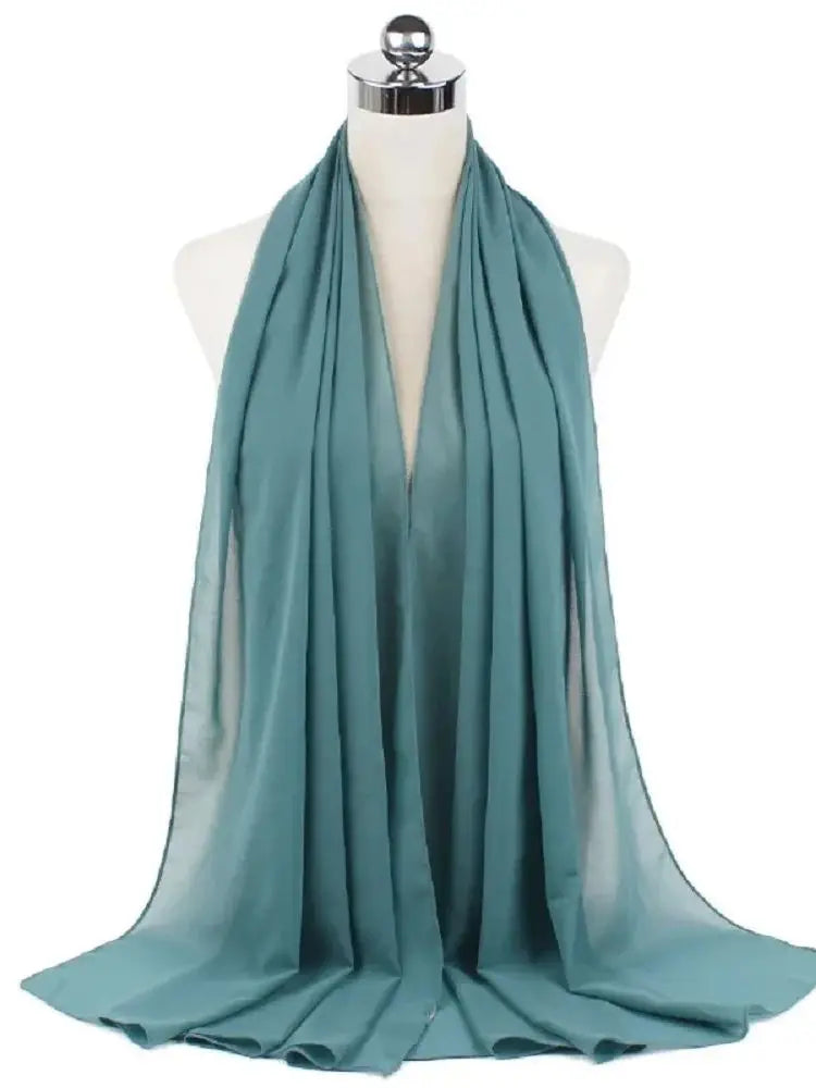 Ein türkis-chiffon-Hijab-Schal, drapiert um den Hals einer Mannequin.