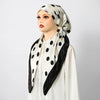A woman wearing an elegant satin silk instant hijab scarf with black polka dots and a black trim.