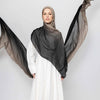 Eine Frau trägt einen schwarzen Ramanda Bamboo Modal Rayon Schal-Hijab über einem weißen Kleid.
