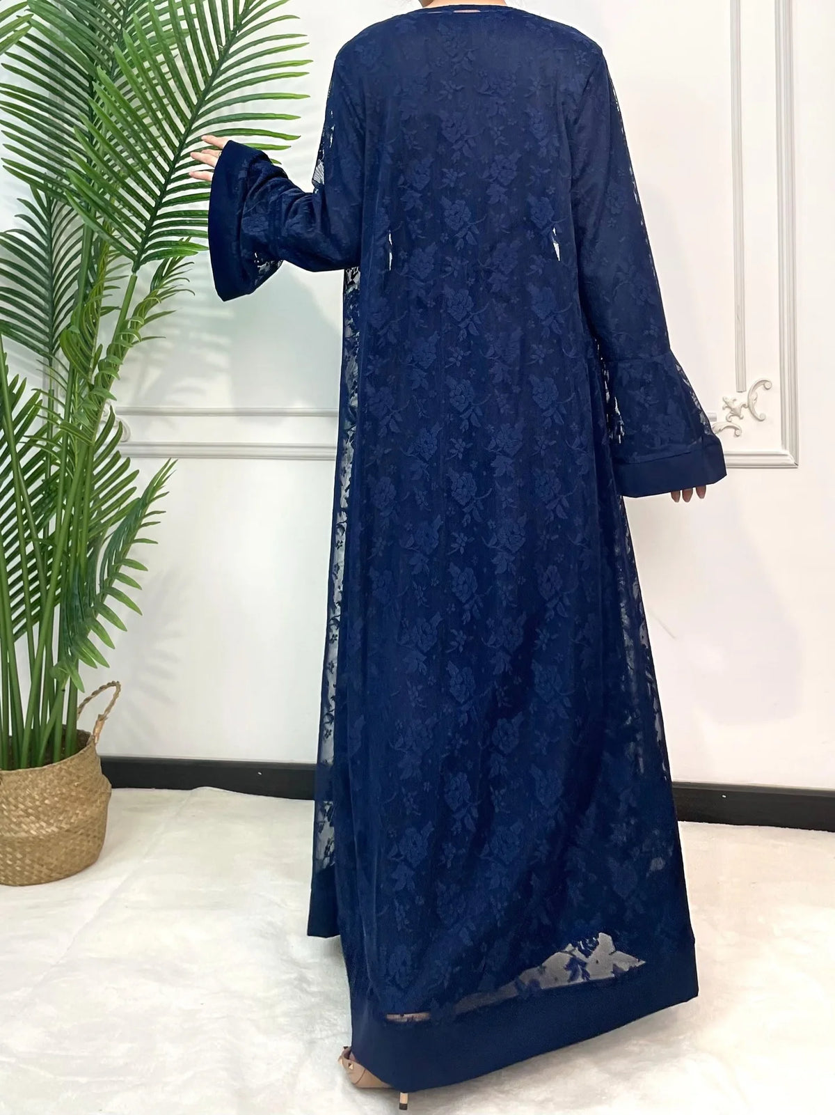 Une abaya en dentelle bleu foncé pour femmes, présentée sur un cintre sur fond blanc.