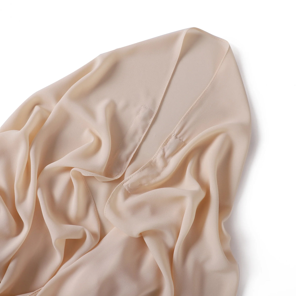 Fließender, hellbeiger Chiffon-Schal sanft über einer weißen Fläche drapiert.