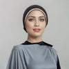 Eine Frau trägt einen schwarzen Hijab mit einem funkelnden Kristallriemen und einem grauen Kleidungsstück.
