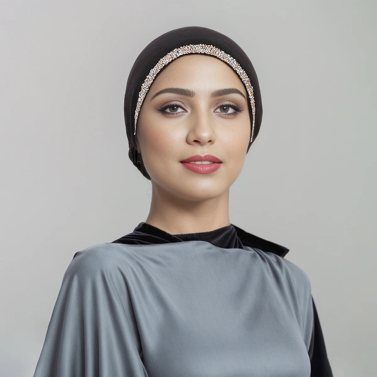 Eine Frau trägt einen schwarzen Hijab mit einem funkelnden Kristallriemen und einem grauen Kleidungsstück.
