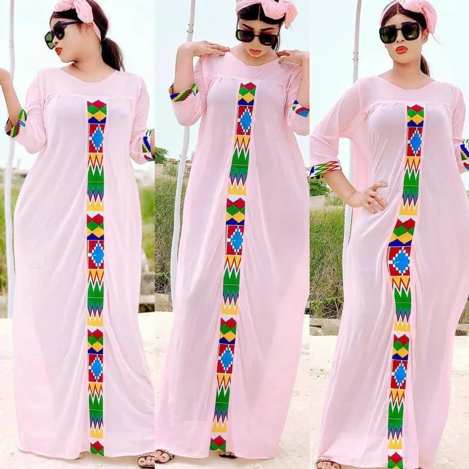 Drei Modelle tragen rosa Kaftane mit farbenfroher Stickerei und Sonnenbrillen