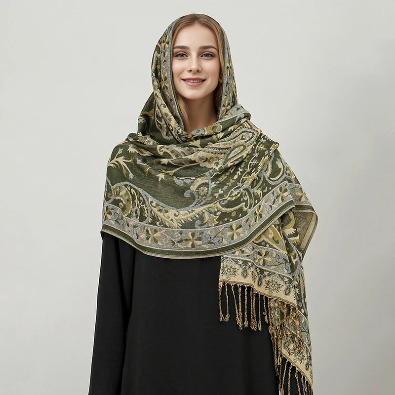 Una mujer modela un pañuelo pashmina de lujo con patrón verde oliva y beige drapeado sobre una prenda negra.