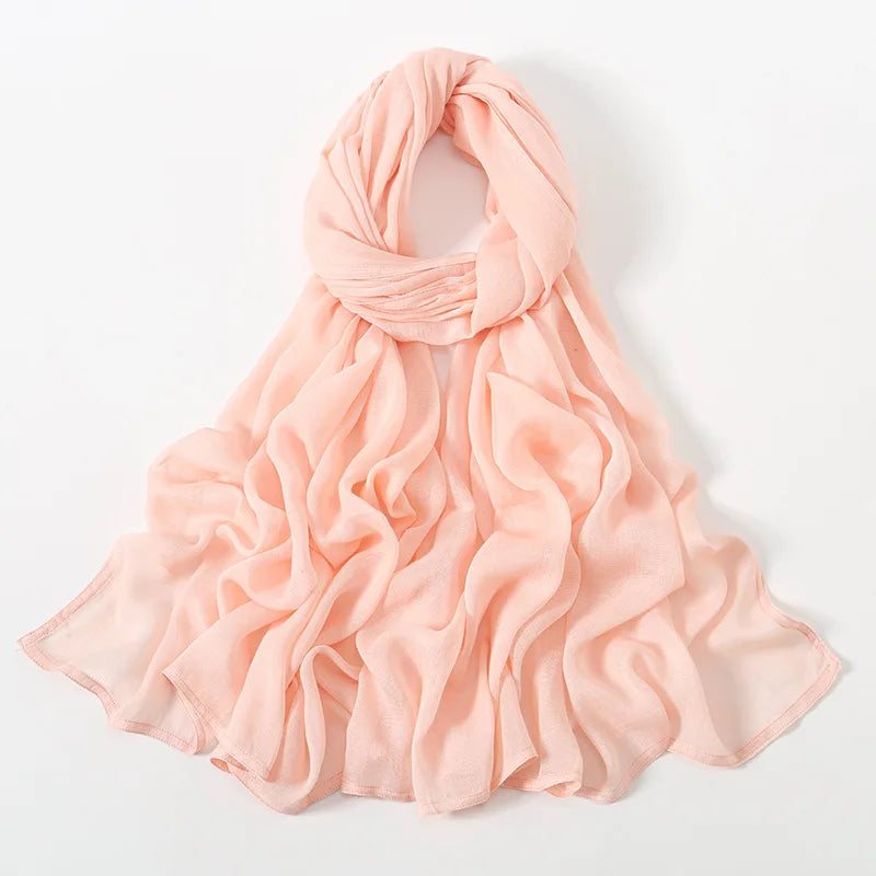 Un gran pañuelo de hijab de modal de color melocotón, fruncido y doblado sobre un fondo blanco.