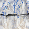 Kleid mit blau-weißem Muster, blauer Blumenstickerei und schwarzer Reißverschlussschließe vorne
