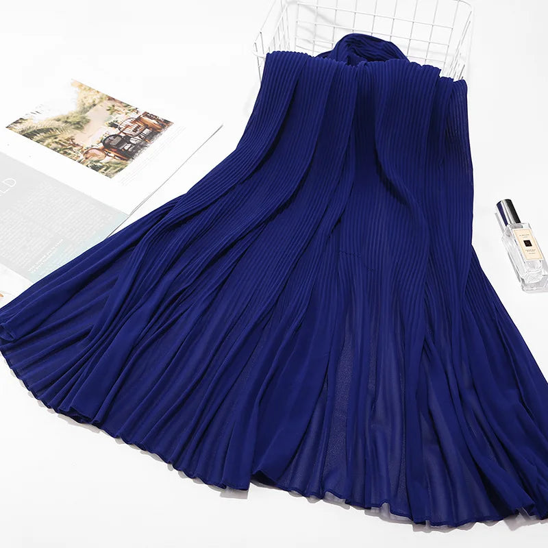 Tiefblaue crinkelige Chiffon-Hijab-Schal, drapiert und auf einer weißen Oberfläche präsentiert.