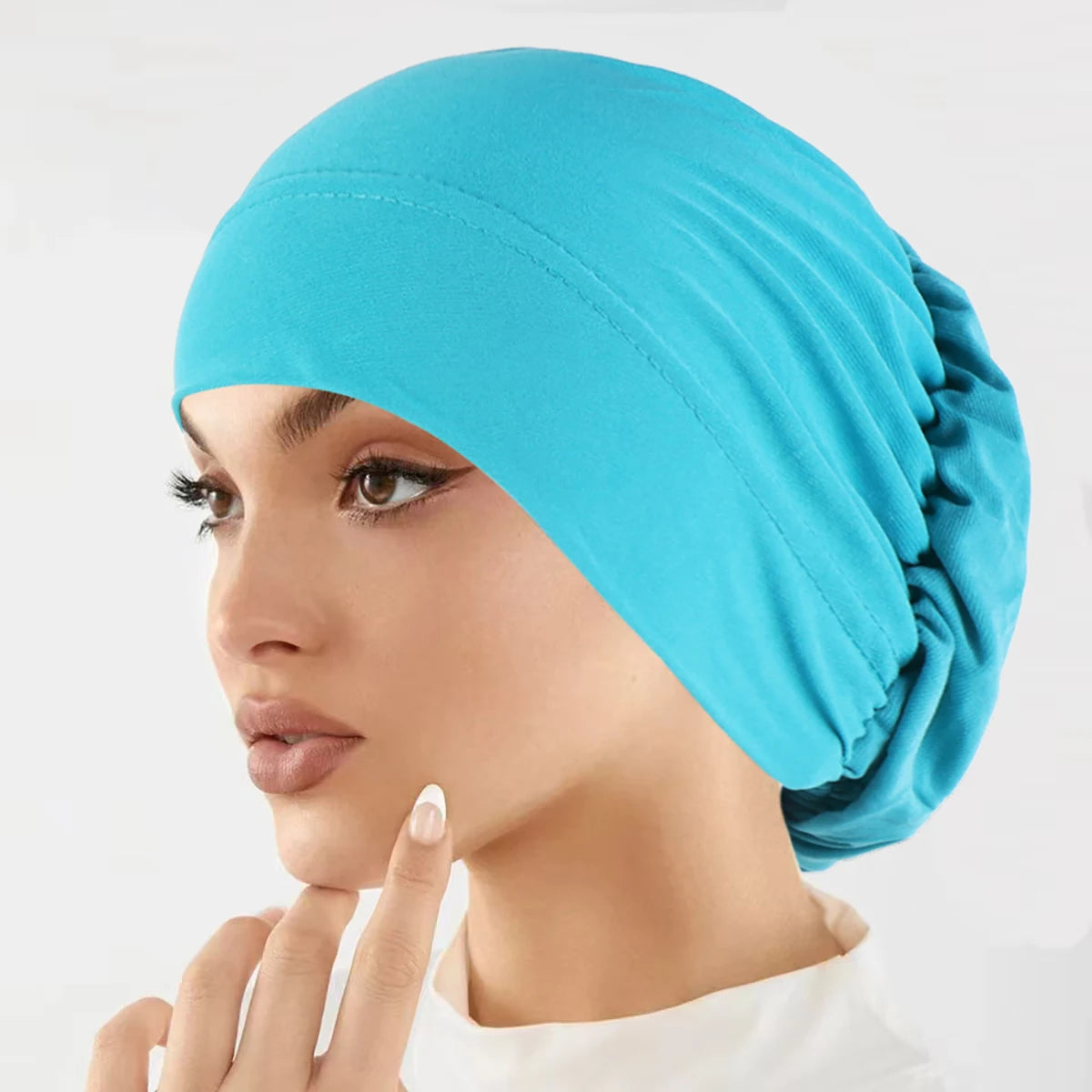 Eine Frau trägt eine leuchtend blaue Stretch-Turbanmütze auf dem Kopf.