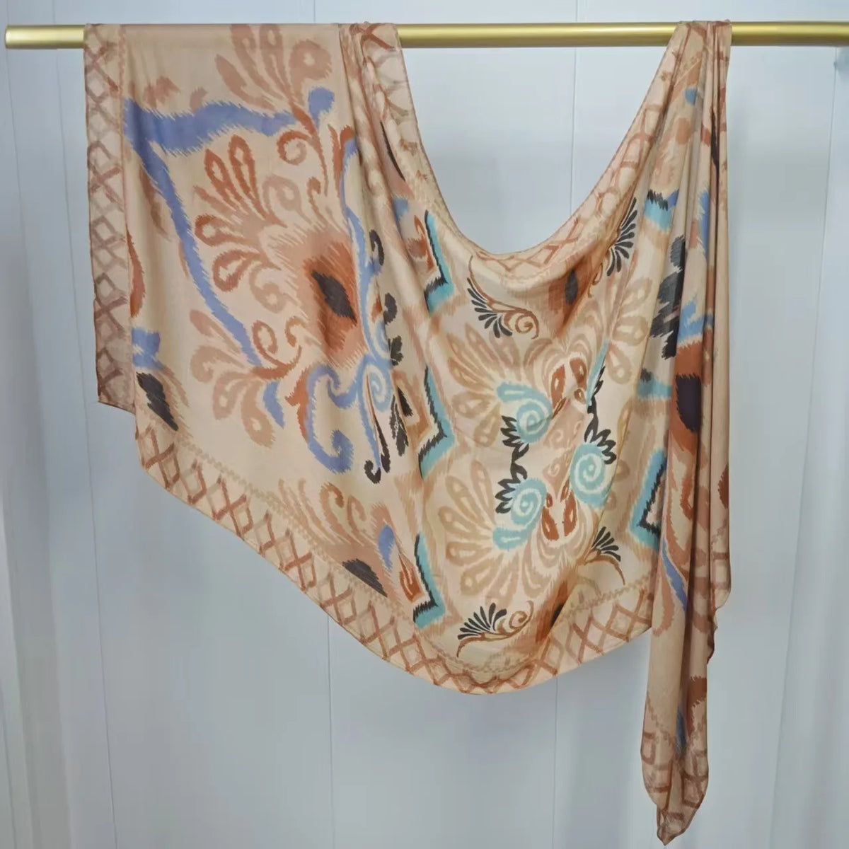 Mehrfarbiger Hijab-Schal, drapiert über einem Holzbügel.