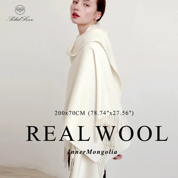 A woman models a cream colored wool shawl draped over her shoulders.
