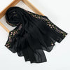 Black chiffon hijab shawl with delicate pink floral embroidery draped over a wooden frame.