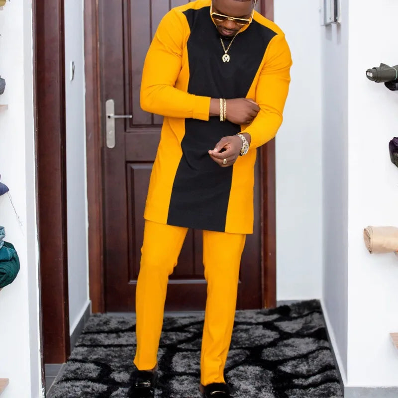 Un homme en costume de mariage musulman traditionnel africain jaune et noir debout dans une porte.