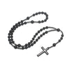 Pendentif croix en hématite noire avec petites perles noires sur une fine chaîne.