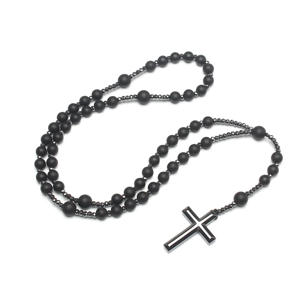 Pendentif croix en hématite noire avec petites perles noires sur une fine chaîne.