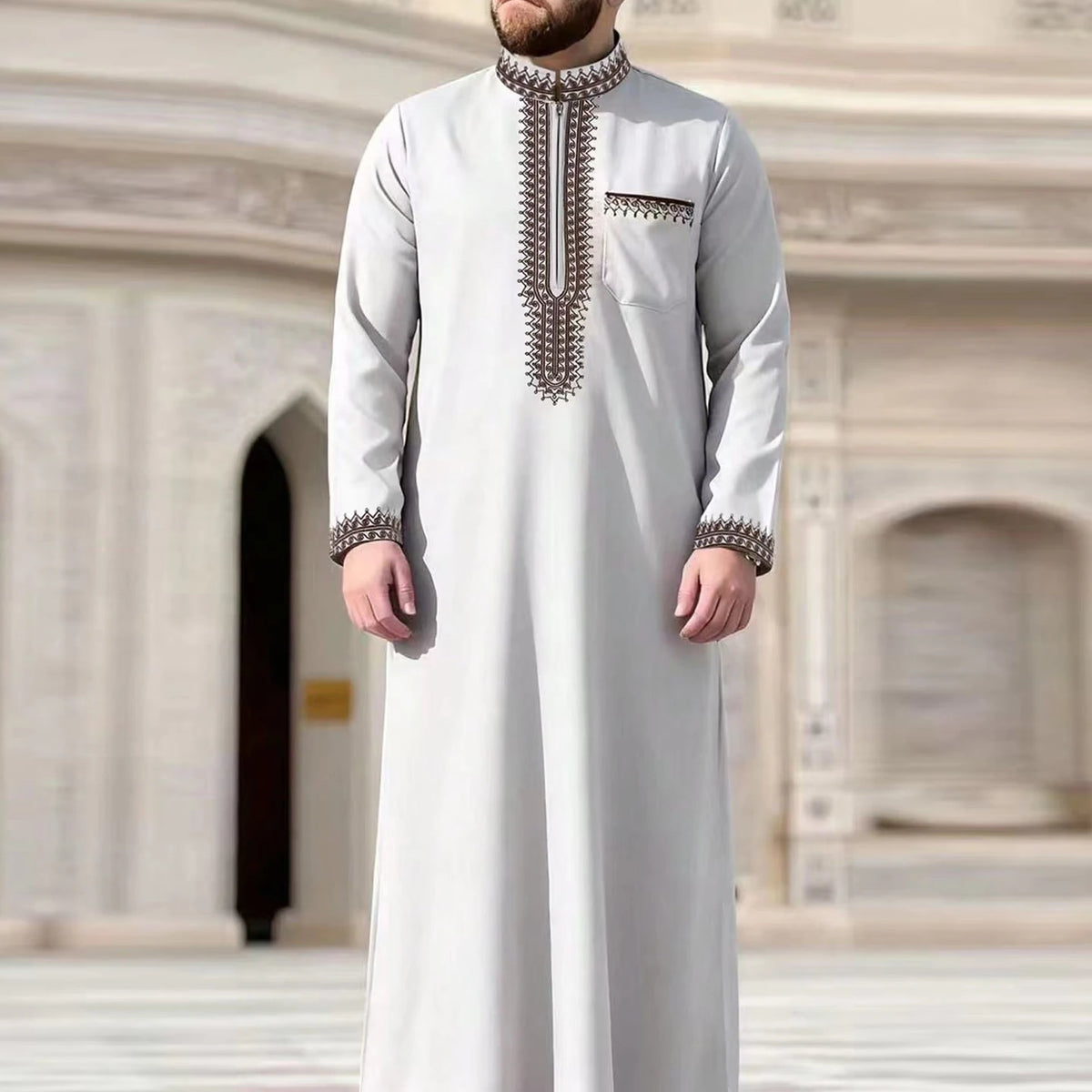 A man wearing a light gray Moroccan embroidered thobe jellaba with silver beadwork collar and cuffs.