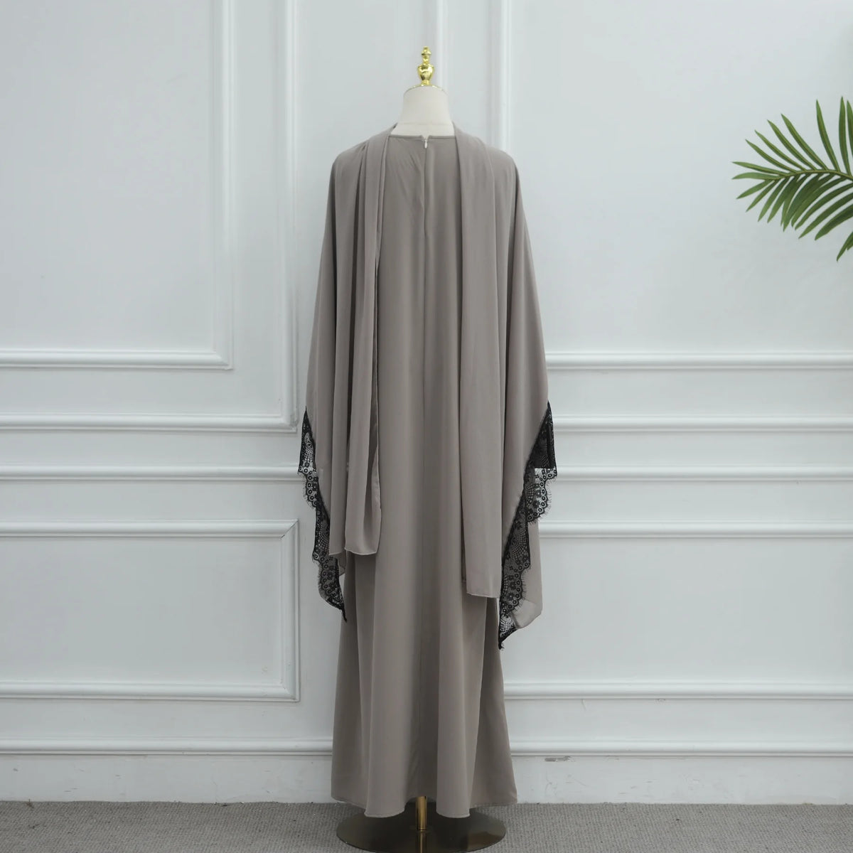Vestido abaya largo y suelto color topo con detalles de encaje negro en las mangas y el dobladillo.