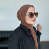 Una mujer vistiendo un hijab instantáneo marrón y gafas de sol, mirando hacia un lado.