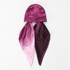 Leuchtend magentlicher Satin-Turban-Hijab-Schal, drapiert und gefaltet auf weißem Hintergrund.