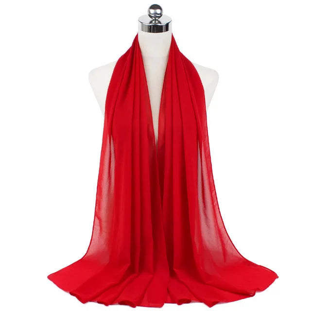 A vibrant red chiffon hijab scarf draped around a mannequin's neck.