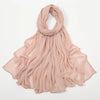 Écharpe en crêpe de rayon rose pâle drapée élégamment autour du cou et des épaules.