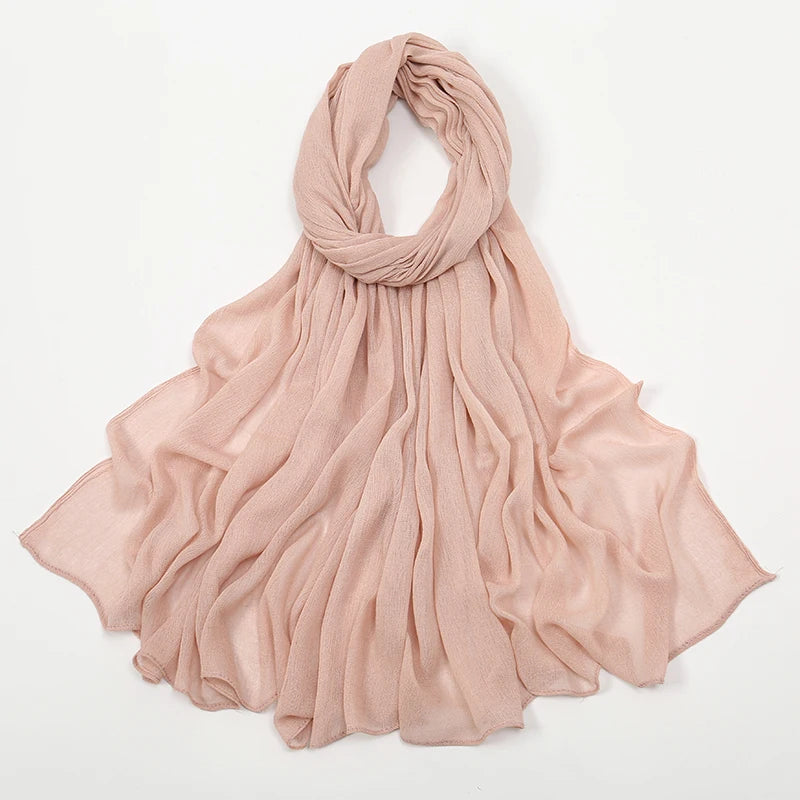 Écharpe en crêpe de rayon rose pâle drapée élégamment autour du cou et des épaules.