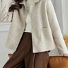 Une femme portant un manteau beige en laine à boutons sur un col roulé blanc et un pantalon marron.