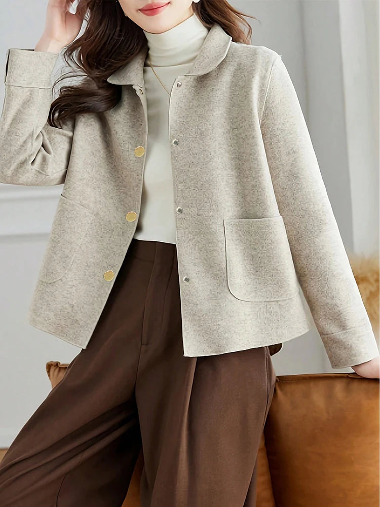 Une femme portant un manteau beige en laine à boutons sur un col roulé blanc et un pantalon marron.